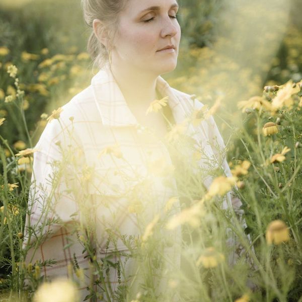 Woman meditating peacefully outdoors with soft, natural light.